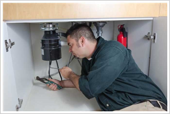 A professional plumber fixing a broken garbage disposal