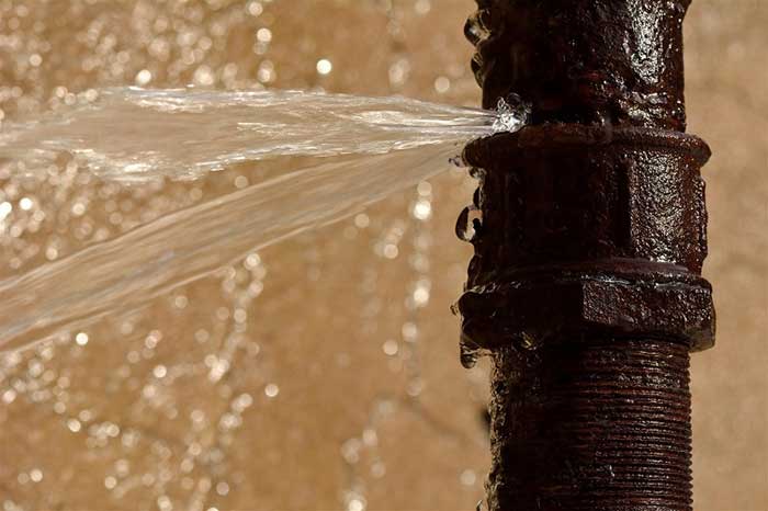 A plumbing pipe with a leak and water coming out of it