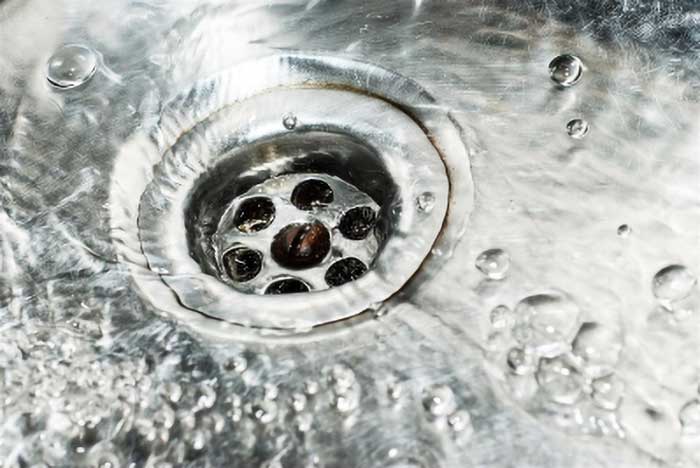 A grease trap with water running down the drain